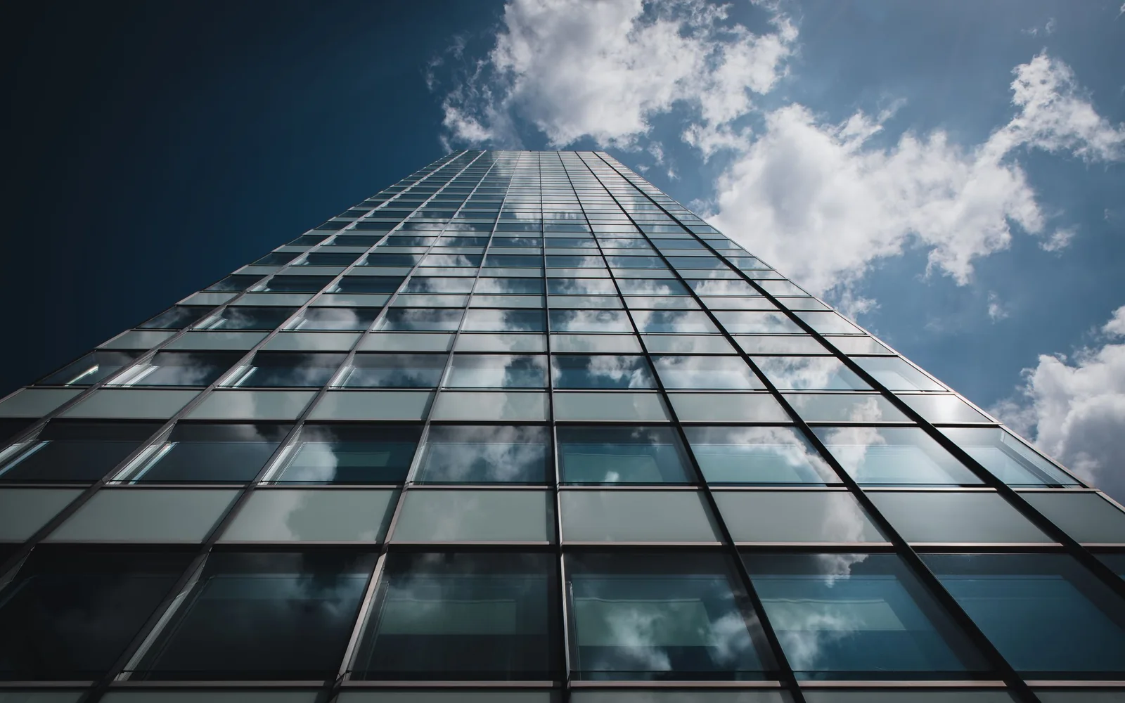 A modern glass office tower against a blue sky