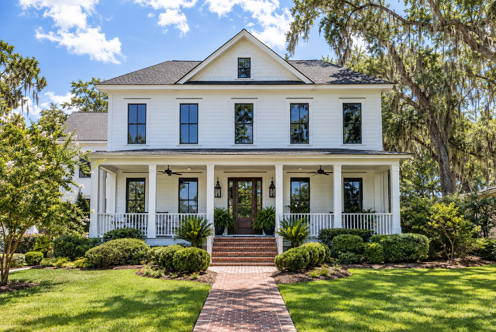 A white Lowcountry home with a deep front porch, its windows evenly tinted