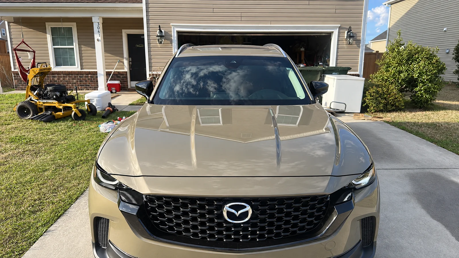 A gold Mazda CX-50 after window tinting, parked on the driveway