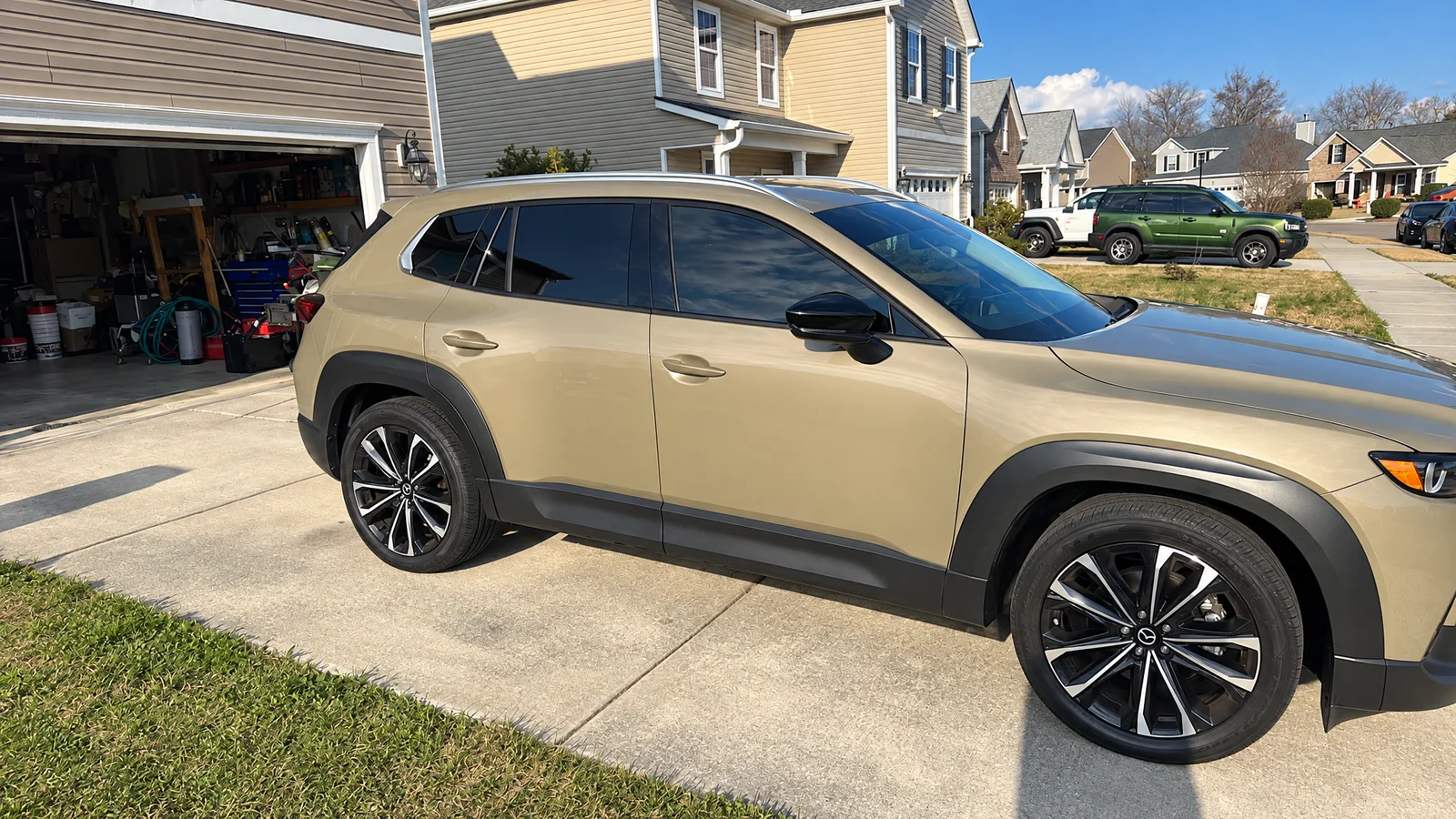 A gold Mazda CX-50 with tinted windows on a driveway