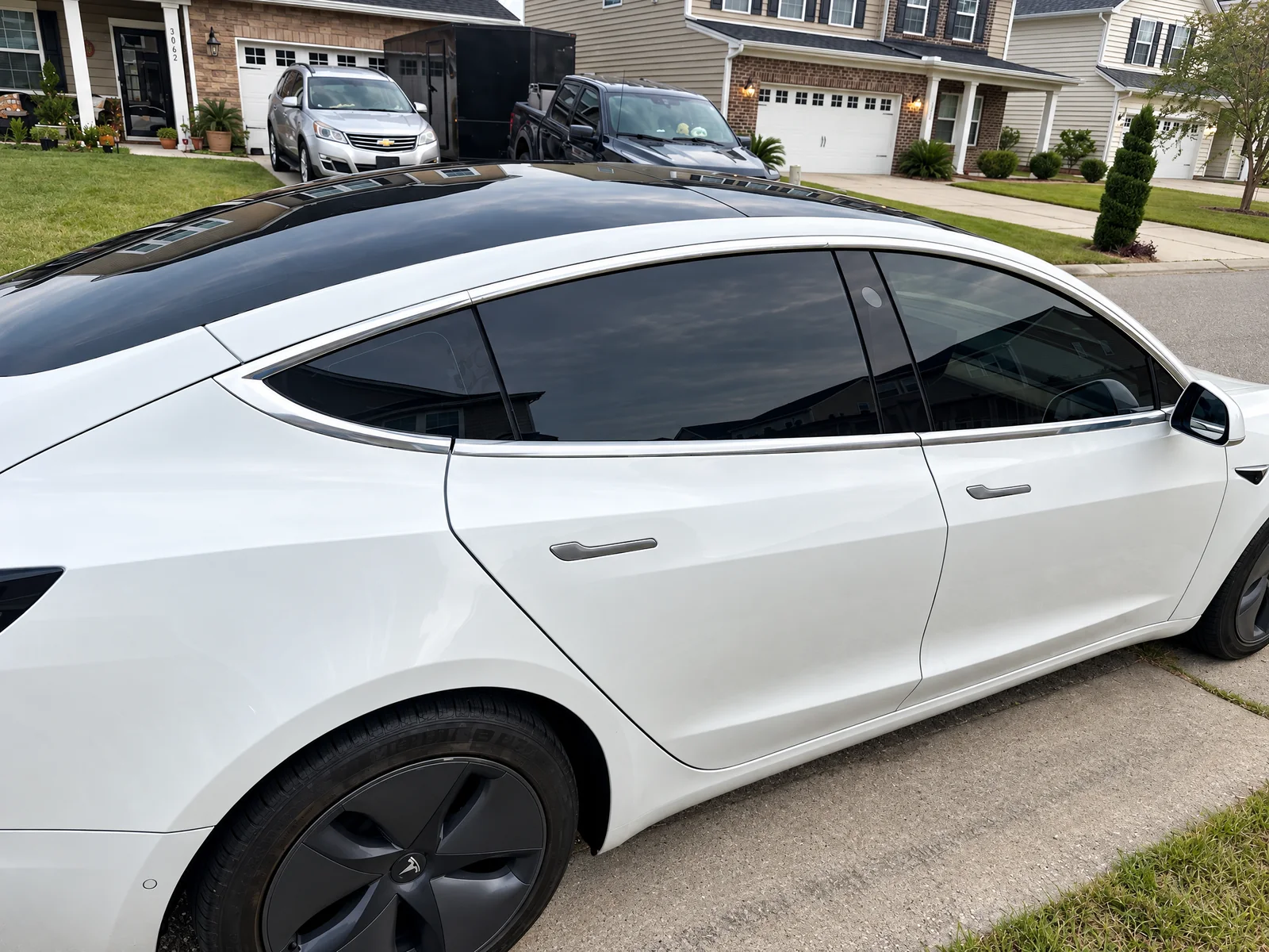 A white Tesla Model 3 with dark tinted side windows